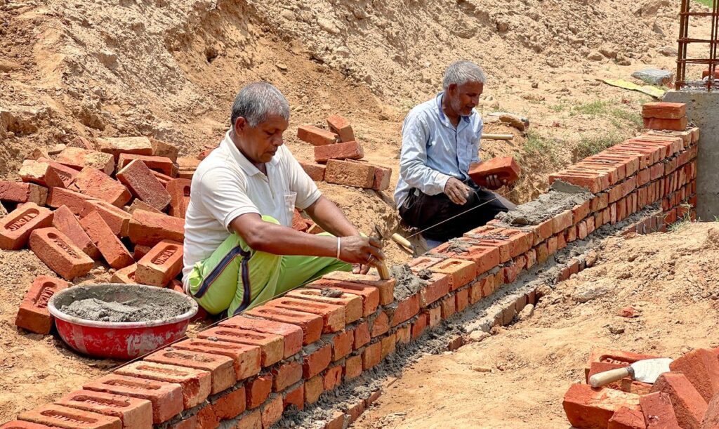 Two men laying bricks at a construction site in Rasulpur, India.